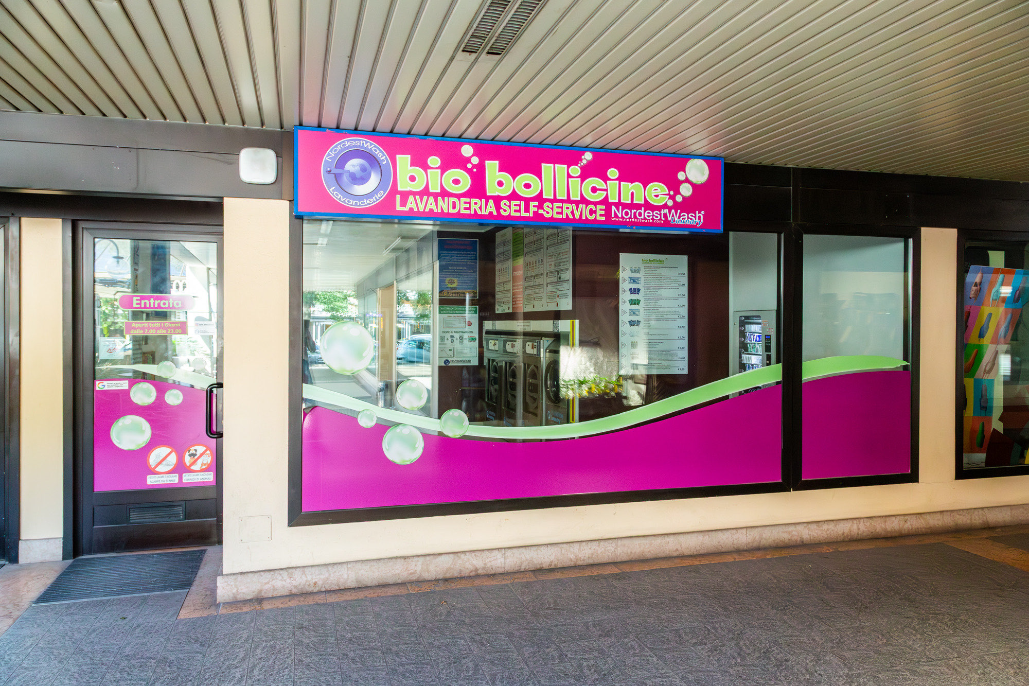 Ingresso della lavanderia self-service Bio Bollicine a Darfo Boario Terme con insegna magenta e verde